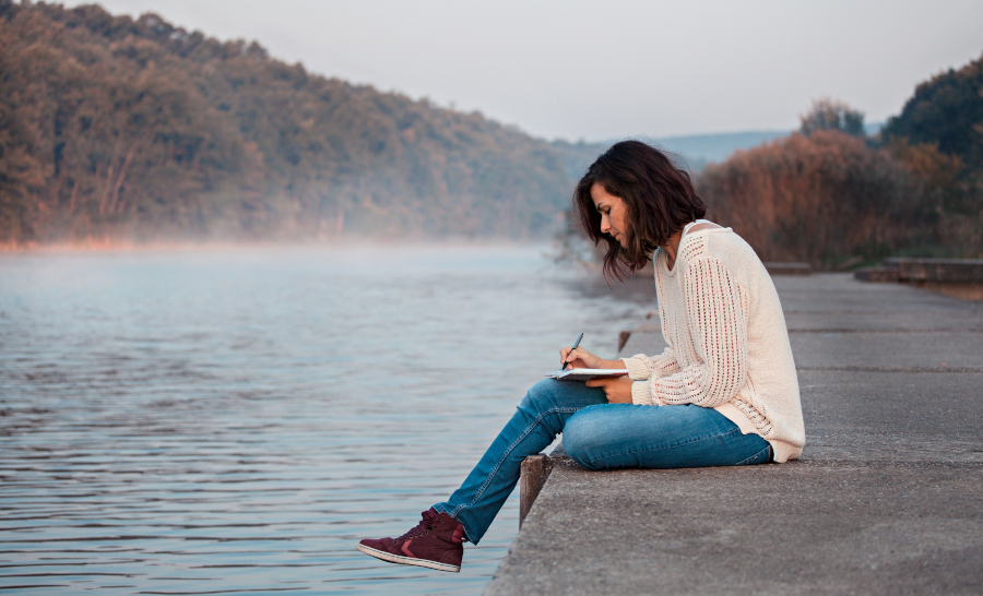 Junge Frau mit Skizzenbuch am See